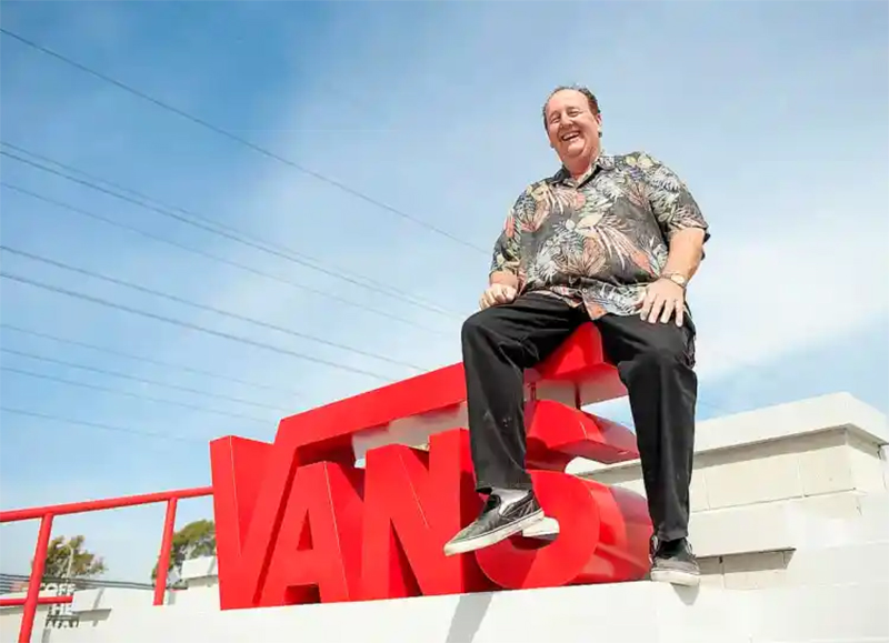 fundador de la marca vans sentado sobre el logo de la marca